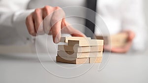 Businessman stacking wooden pegs