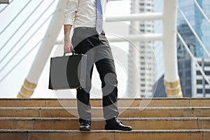 Businessman stand alone holding document bag at ladder after working