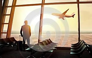 Businessman standing at the airport window waiting for departure