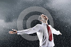 Businessman standing arms spread facing incoming rain