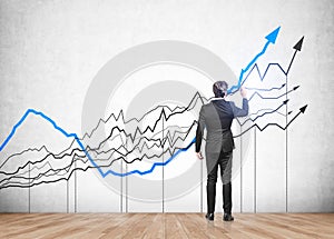 Businessman standing back view and drawing lines, rising stock market