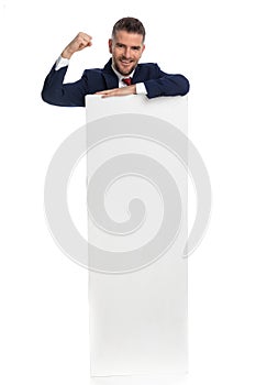 Businessman standing behind his billboard and celebrating success