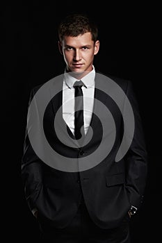 Businessman standing on black background. handsome young Man in suit