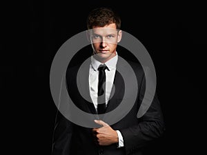 Businessman standing on black background. handsome young Man in suit