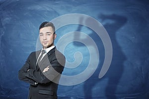 Businessman standing on blue background with a shadow with hands on head behind him