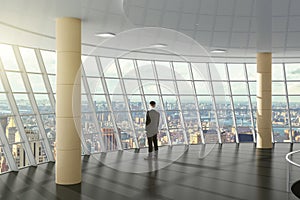 Businessman standing in a business center hall with city view
