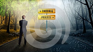 Businessman standing at a crossroad with road signs `theory ` and `praxis ` in German photo