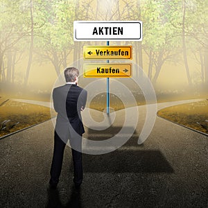 Businessman standing on a crossroad, having to choose the right path what to do with the words shares, sell and buy