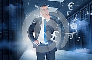 Businessman standing in data center with currency graphics