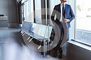 businessman standing at departure lounge and looking at window