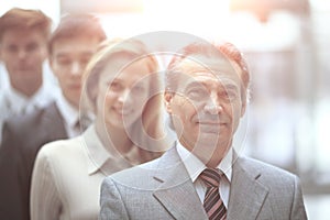 Businessman standing in front of his business team on blurred office background