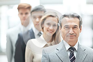 Businessman standing in front of his business team on blurred office background