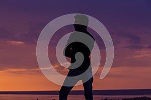 Businessman standing in front of the sea at sunset, side profile of man standing thinking of future