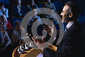 Businessman standing and giving presentation in the auditorium