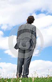 The businessman standing on a green grass