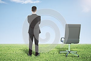 Businessman standing on a green grass and looks away