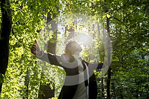 Businessman standing with his arms outspread in woodland photo