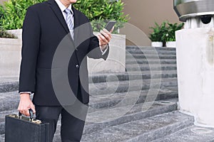 Businessman standing and holding a briefcase in hand working wit