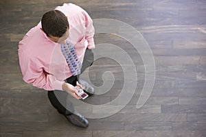 Businessman standing indoors looking at phone