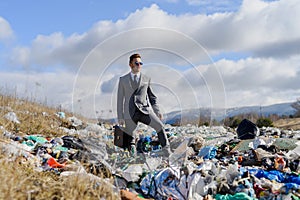 Businessman standing on landfill, large pile of waste. Consumerism versus pollution concept. Corporate social