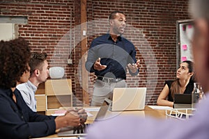 Businessman Standing And Leading Office Meeting Around Table