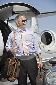 Businessman Standing With Luggage At Airfield photo
