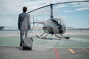 Businessman standing near private helicopter