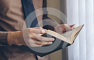 Businessman standing near window and reading book vintage tone