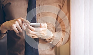 Businessman standing near window and using cell phone vintage tone