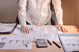 Businessman standing in office with papers laid on the table. Concerns and business planning.
