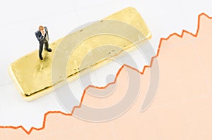 Businessman standing on the price chart with gold bar