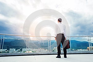 Businessman standing on a roof and looking at city Success and t