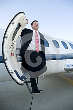 Businessman standing on the steps of corporate jet