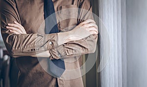 Businessman standing thinking and cross one`s arm near window