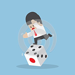 Businessman standing on unstable dice photo