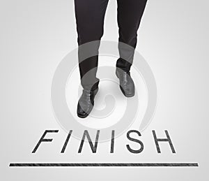 Businessman standing wearing court shoes on finish line.