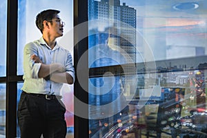 Businessman standing at window of office building overlooking at cityscpae. photo