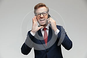 Businessman standing and yelling on the phone angry