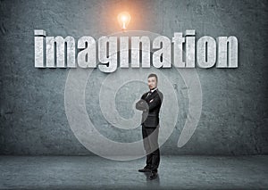 Businessman stands with big 3d 'imagination' word above