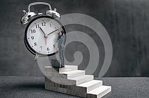 Businessman stands on stairs and tries to change clock hand