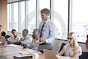 Businessman Stands To Address Meeting Around Board Table