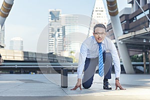 Businessman start kneeling city street race business goal winner challenge. Asian man look at camera smile face wear glasses. Man