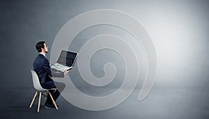 Businessman staying in an empty room with stuffs on his lap