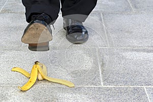 Businessman stepping on banana skin, work accident, copy space