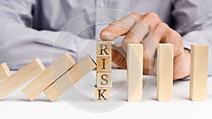 Businessman stop domino effect with word Risk