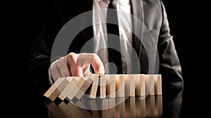 Businessman Stopping the Domino Effect