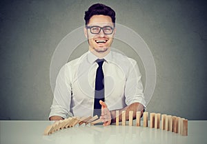 Businessman stopping the domino effect