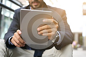 Businessman on street using iPod. Focus on hands.