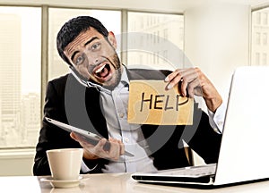 Businessman in stress holding help sign multitasking overwhelmed in business district office photo