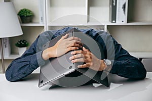 Businessman stressed laid his head down on the table with laptop